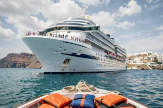 Grand navire de croisière moderne naviguant en Méditerranée avec Santorin en arrière-plan