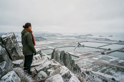 Randonneuse au sommet de la Pointe du Salaison en hiver contemplant le panorama sur les étangs côtiers